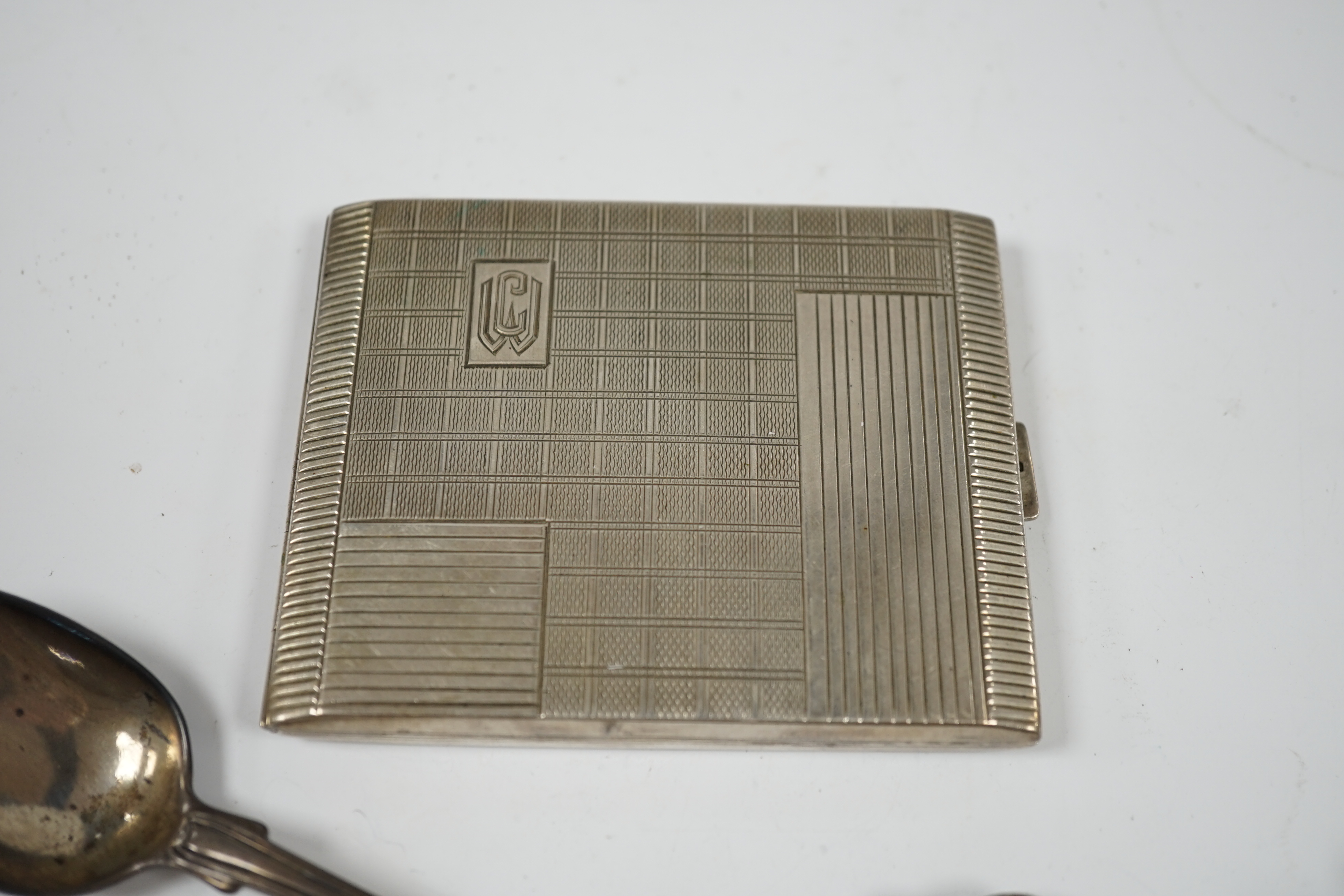 An Art Deco German? 800 standard white metal cigarette case, a white metal mesh evening bag and two similar purses and a Victorian silver fiddle and thread pattern teaspoon. Condition - poor to fair
